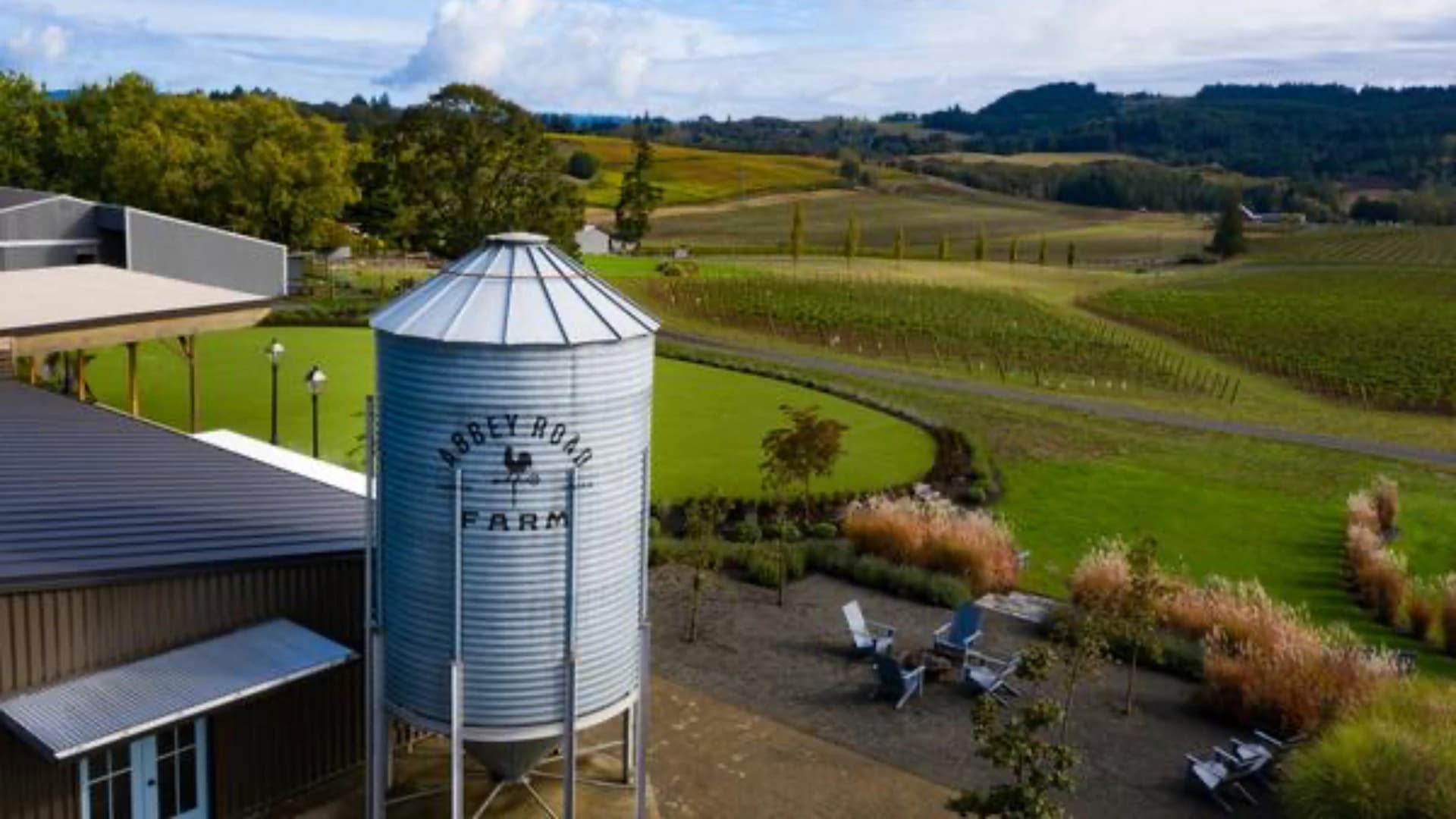 A silver farm silo labeled "Abbey Road Farm" with a vineyard and rolling hills in the background.