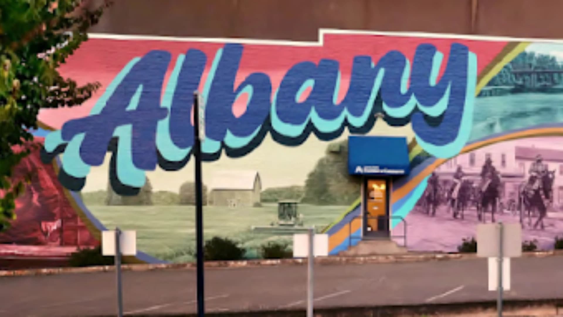 Large mural sign reading ALBANY showing people on horsed